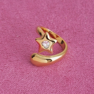Gros plan d'une bague étoile dorée ajustable avec zircon brillant sur tissu rose