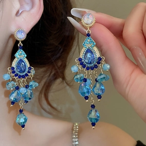 Macro view of blue crystal fringe earrings with intricate silver needles and gold base