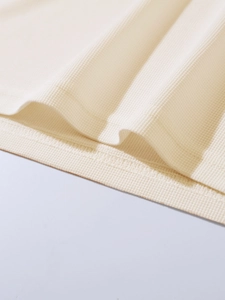 Close-up of beige waffle knit fabric texture and high-quality hem stitching on polo shirt
