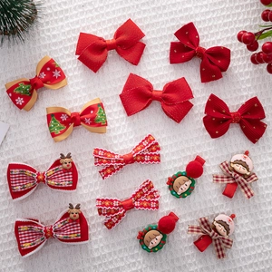 Flat lay of festive Christmas hair clips set with red bows and elk motifs on white fabric