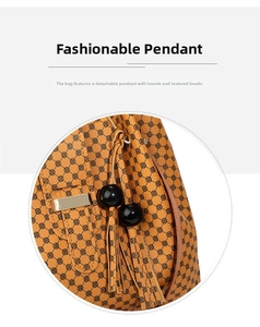 Detail of caramel leather handbag with floral pattern and removable tassel charm