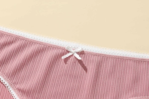 Close-up of pink ribbed fabric panties with delicate white lace trim and a small bow detail