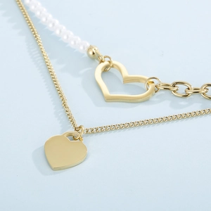 Close-up of double-layered gold necklace with heart charms and white pearls