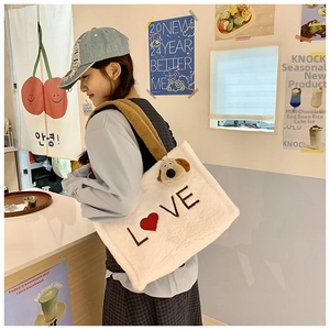 Close-up of white plush tote bag with LOVE embroidery and cute dog charm detail