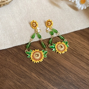 Close-up of vintage sunflower drop earrings with yellow enamel and green crystal beads
