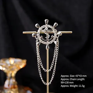 Detail of silver anchor and helm brooch with rhinestones and hanging chains