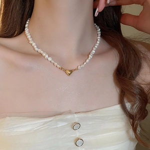 Detailed close-up of 18K gold heart pendant and natural freshwater pearl necklace on neck