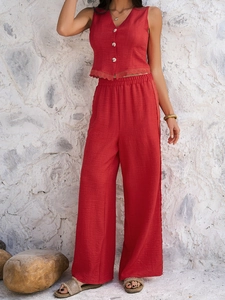 Detail of red two-piece set featuring a buttoned vest with lace hem and wide-leg trousers
