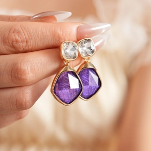 Gros plan détaillé de boucles d'oreilles vintage en or avec pierres violettes et claires