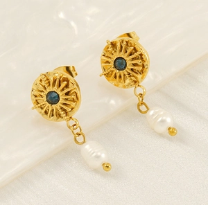 Macro detail of golden sunburst earrings with blue gemstones and white baroque pearls