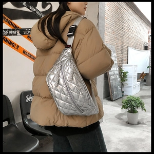 Close-up of a silver quilted puffer fanny pack with adjustable strap worn by a model