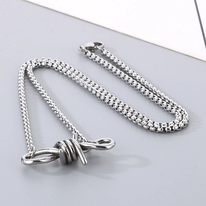 Macro shot of silver stainless steel thorn knot charm on a link chain bracelet