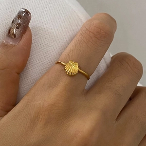 Close-up of golden shell ring with polished scalloped design on model's hand