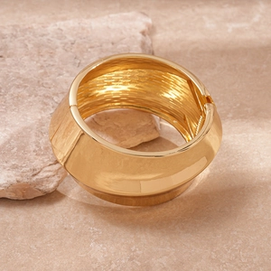 Detailed macro view of glossy gold twisted wide bangle with polished finish and hinged clasp