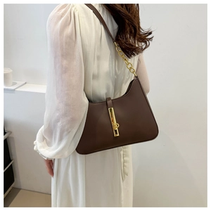 Side view of model wearing a dark brown leather half-moon bag with gold buckle detail