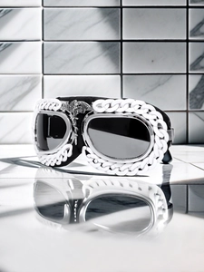 Detail of black sports goggles with white chain decor and silver dragon metal centerpiece
