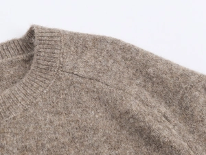 Macro shot of light brown knit sweater texture with ribbed crew neck and fine stitching