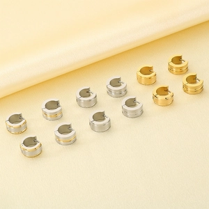 Macro detail of matte brushed stainless steel C-shaped hoop earrings in gold and silver