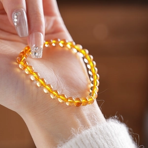 Detailed view of yellow crystal beaded bracelet with round beads worn on female wrist