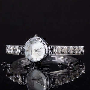 Macro view of mother-of-pearl dial and elegant pearl rhinestone watch strap