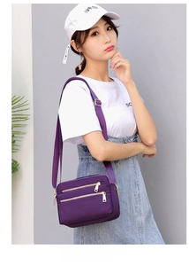Detail of purple waterproof nylon crossbody bag with multiple gold zipper pockets