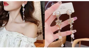Macro detail of long gold tassel earrings with pearls and snowflake design elements