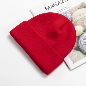 Close-up of red knitted beanie texture with fold-over cuff on lifestyle magazine background