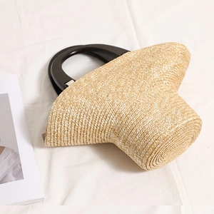 Borsa in paglia con manico in legno scuro su tessuto bianco per uno stile da spiaggia