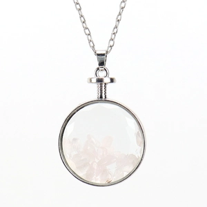 Detail of round glass pendant filled with natural pink crystal stones on silver chain