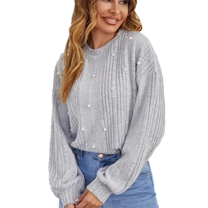 Gros plan sur le pull en maille grise orné de perles blanches et texture côtelée fine