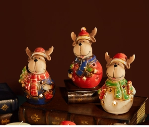 Three ceramic reindeer candle holders with warm light display on vintage books