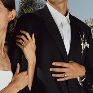 Polished silver stacked rings and necklace on a couple in an elegant outdoor setting