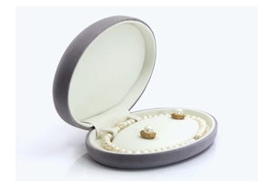 Detail view of oval grey velvet jewelry box with pearl necklace and earrings set
