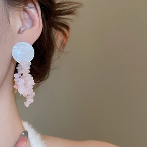 Detailed close-up of pink stone tassel earrings on a model with natural lighting