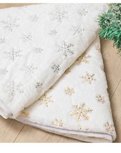 Close-up of white plush Christmas tree skirt with silver and gold snowflake embroidery details