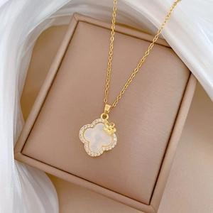Macro detail of gold clover pendant with white mother-of-pearl and sparkling rhinestones