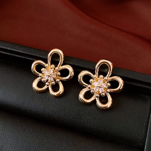 Macro shot of gold floral earrings with cubic zirconia on black leather and red velvet