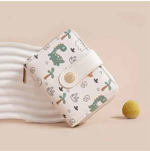 Close-up of cream PU leather wallet with green cartoon dinosaur print and snap closure