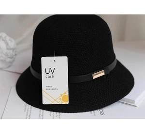 Dettaglio cappello da sole in maglia nera con cinturino in pelle e fibbia dorata