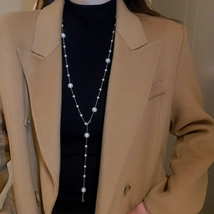 Detail of elegant gold Y-shaped necklace featuring white pearls on a long chain