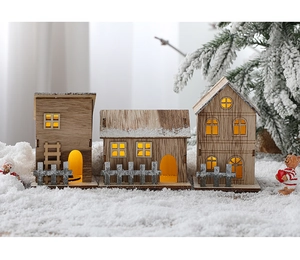 Close-up of three lighted wooden Christmas cabins on a snowy winter background