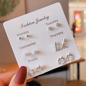 Detail of 6-pair silver earring set featuring hearts and pearls on a weekly card display