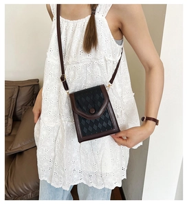 Détail du sac de téléphone noir matelassé avec garniture en cuir marron et boucles dorées
