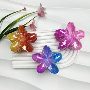 Detailed close-up of glossy gradient plumeria hair claws in yellow, blue and pink