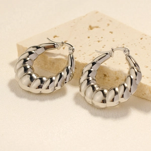 Silver twisted hollow croissant hoop earrings on stone display for women jewelry