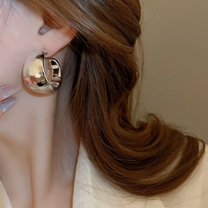 Macro shot of silver C-shaped hoop earring with hammered texture worn by a model