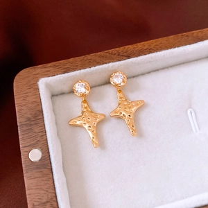 Close-up of 18K gold star earring with zircon in a velvet lined wooden jewelry box