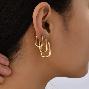 Close-up of a three-piece gold U-shaped rectangular hoop earring set worn by a model