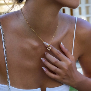 Close-up of a gold heart pendant necklace with rhinestones worn by a model