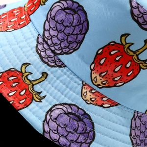 Detailed view of light blue fruit print bucket hat with strawberry and mulberry patterns